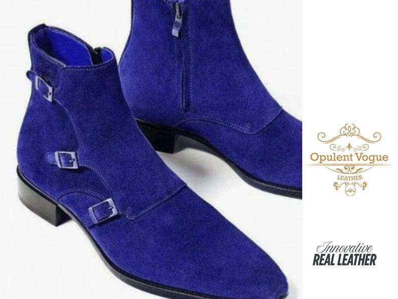 May include: A pair of bright blue suede ankle boots. One boot has two buckle fastenings, while the other has a zip. The boots have a pointed toe and a low heel. The image also includes the text "Opulent Vogue Leather" and "Innovative Real Leather".
