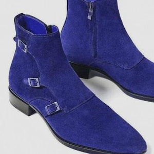 May include: Cobalt blue suede ankle boots with pointed toes. The boots have double buckle fastenings and a side zip. The heels are low and stacked.