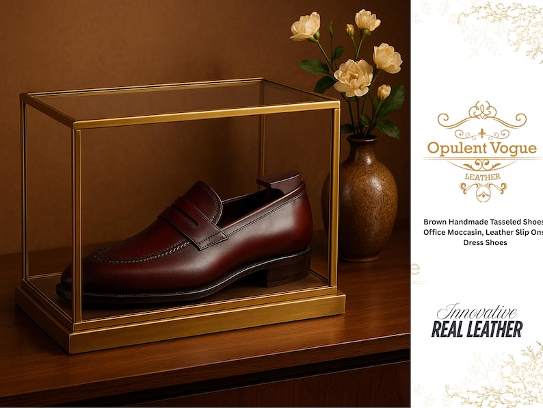 May include: A brown leather loafer displayed in a glass and gold frame. The shoe is a dress shoe with a tasseled design. The image also includes a vase with flowers and the text "Opulent Vogue Leather".