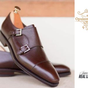 Zapatos de vestir de cuero marrón hechos a mano con doble hebilla y puntera reforzada.