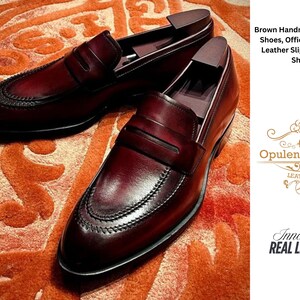 May include: A pair of brown leather slip-on dress shoes with a decorative stitched design. The shoes are displayed on an orange patterned surface. The image includes the text "Brown Handmade Tasseled Shoes, Office Moccasin, Leather Slip Ons, Dress Shoes."