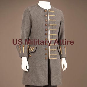 May include: A grey military-style coat with gold trim and buttons. The coat features a mandarin collar, long sleeves, and decorative gold accents on the cuffs and pockets. The text "US Military Attire" is printed on the coat.