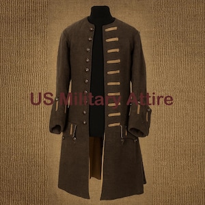 Puede incluir: Un abrigo largo marrón con botones y detalles en beige. El abrigo tiene un cuello alto y lleva la inscripción "US Military Attire". Diseño clásico.