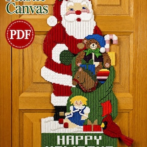 May include: A plastic canvas craft pattern featuring Santa Claus holding a green sack filled with toys, including a teddy bear, a doll, and a rocking horse. The design includes a red cardinal, holly leaves, and the text Happy Holidays in white.