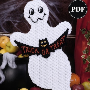 Pode incluir: Uma decoração de fantasma em tela plástica branca com um morcego preto no centro com o texto laranja TRICK OR TREAT. O fantasma tem olhos e boca costurados em preto. O texto Plastic Canvas e PDF é visível no topo da imagem.
