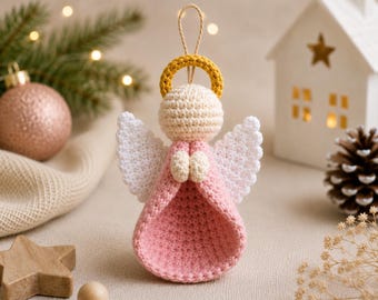 May include: A crocheted angel ornament featuring a pale pink dress, a cream-colored head, and white wings. The figure has a golden yellow halo and a small loop of twine at the top for hanging. The hands are positioned together in front of the chest.