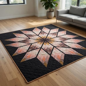May include: A large, black quilt with a central starburst design. The starburst features shades of peach, brown, and gold, with a geometric pattern. The quilt is placed on a hardwood floor.