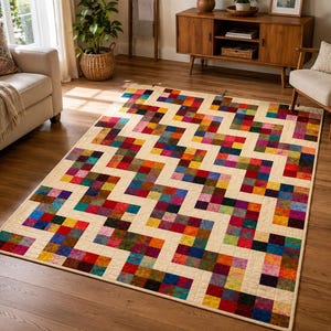 May include: A rectangular area rug featuring a repeating zigzag pattern composed of small, multicolored square patches in shades of red, blue, yellow, green, and purple, separated by solid cream-colored fabric borders throughout the design.