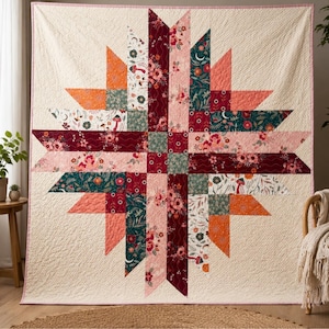 Puede incluir: Una colcha cuadrada con un patrón de estrella central compuesto por varios parches de tela. El diseño incluye motivos florales, de setas y de lunas crecientes en tonos crema, burdeos, verde oscuro, naranja y rosa, con costuras acolchadas visibles.