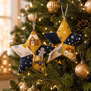 May include: Two star-shaped fabric ornaments featuring a patchwork design of navy blue, mustard yellow, and white cotton. The patterns include gingerbread men, houses, and snowflakes. Each point of the stars is accented with a small yellow pom-pom.
