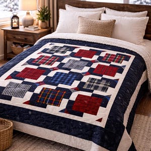 May include: A navy blue and white quilt with a patchwork design featuring red, blue, and plaid squares. The quilt is on a bed with white pillows and a woven pillow. The room has a rustic wooden nightstand and a snowy window.