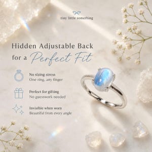 Puede incluir: Un anillo plateado con una piedra preciosa ovalada azul. El anillo se muestra sobre una superficie blanca con peque&ntilde;as flores y cristales blancos. El texto de la imagen dice: "Hidden Adjustable Back for a Perfect Fit."