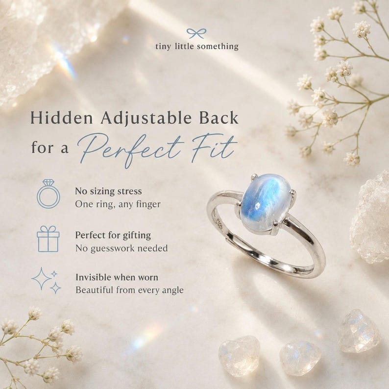Puede incluir: Un anillo plateado con una piedra preciosa ovalada azul. El anillo se muestra sobre una superficie blanca con peque&ntilde;as flores y cristales blancos. El texto de la imagen dice: "Hidden Adjustable Back for a Perfect Fit."