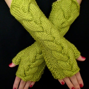 Peut inclure: Une paire de mitaines sans doigts en tricot vert avec un motif de câble.