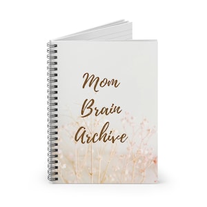 Könnte beinhalten: Ein spiralgebundenes Notizbuch mit weißem Einband. Auf dem Einband steht in brauner Schrift "Mom Brain Archive". Es hat ein zartes Blumendesign in neutralen Tönen. Das Notizbuch ist geöffnet und zeigt linierte Seiten.