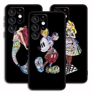 Könnte beinhalten: Drei schwarze Handyhüllen mit verschiedenen bunten Comicfiguren-Designs. Die erste Hülle zeigt eine Meerjungfrau mit einem blauen Schwanz und rosa Haaren. Die zweite Hülle zeigt Mickey Mouse mit einem rot-schwarzen Design. Die dritte Hülle zeigt Alice im Wunderland mit einem blau-weißen Kleid.