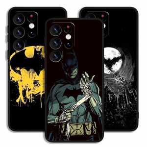 Könnte beinhalten: Drei schwarze Handyhüllen mit Batman-Designs. Eine Hülle hat ein gelbes und schwarzes Batman-Logo mit einem Spritzeffekt. Eine andere zeigt Batman, der sich die Hände verbindet. Die dritte zeigt eine Stadtlandschaft mit einem Fledermaussymbol.