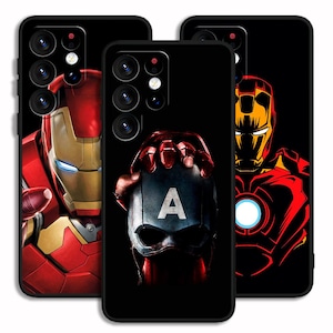 May include: Three black phone cases featuring superhero designs. One case displays Iron Man's face in red and gold, another shows Captain America's shield, and the third features Iron Man's outline.