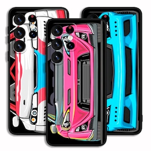 May include: Three phone cases with car designs. The cases feature illustrations of cars in white, pink, and blue. Each case has a black border and a camera cutout. The car designs are detailed and stylized, with visible headlights and other features.