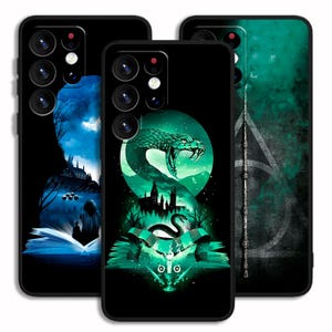 May include: Three black smartphone cases featuring fantasy-themed illustrations. The left case shows a blue scene with a castle and an open book. The centre case displays a green snake, a castle, and a book. The right case features a wand and a triangle symbol.