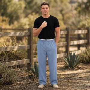 May include: A black short-sleeved crew neck t-shirt paired with light blue trousers featuring a subtle vertical pinstripe pattern, an elasticized waistband, and a white inner lining visible at the top edge of the pants.