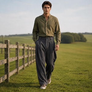 May include: An olive green long-sleeved button-down shirt with a mandarin collar paired with loose-fitting charcoal gray pleated trousers and light-colored sneakers. The clothing features a simple design with visible buttons on the shirt front.