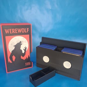 May include: A black VHS tape-shaped storage box with a red and black "Werewolf" design, a separate black tray, and a matching box. The design features a howling wolf silhouette against a full moon. The boxes are on a blue background.