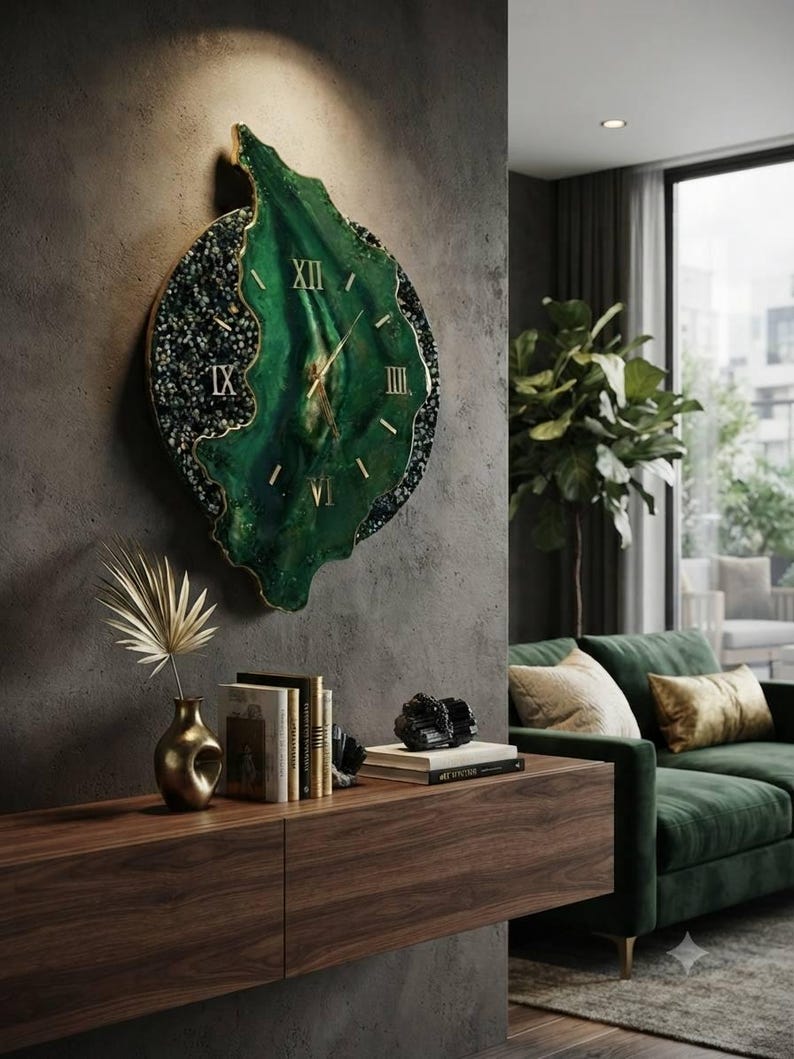 May include: A large, irregular wall clock featuring a deep green, marbled resin face with gold-colored Roman numerals and thin gold hands. The outer edge is textured with dark, crushed stone-like accents and a thin gold metallic border.