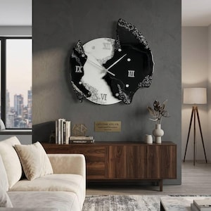 May include: A wall clock featuring a circular white center with Roman numerals and silver hands, flanked by two irregular, textured black resin sections with silver glitter accents. The clock face displays the numerals XII, III, VI, and IX.
