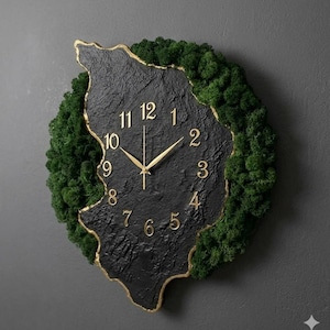 May include: A wall clock featuring a textured black, irregular-shaped face with gold-colored numerals and hands. The perimeter of the clock is framed by dense, vibrant green preserved moss, creating a contrast between the dark stone-like center.