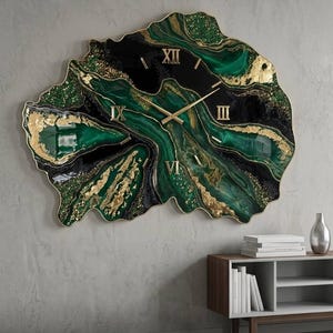 Op de afbeelding: Een onregelmatige wandklok in geode-stijl met een wervelend patroon van diep smaragdgroen, zwart en metallic bladgoudaccenten. De wijzerplaat toont gouden Romeinse cijfers op de posities twaalf, drie, zes en negen uur.