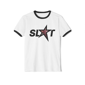 Puede incluir: Camiseta blanca con ribete negro alrededor del cuello y las mangas. La camiseta presenta la palabra "SLXT" en letras negras, con un gr&aacute;fico de estrella en lugar de la "A". La estrella tiene un dise&ntilde;o rosa y rojo.