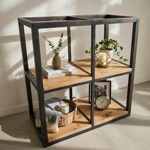 Könnte beinhalten: Industrieller Bücherschrank mit vier Regalen, schwarzem Metallrahmen und hellen Holzregalen. Die Regale sind mit einer Vase, Büchern, einer Kerze, einem Korb, einer Uhr und einem gerahmten Bild dekoriert.