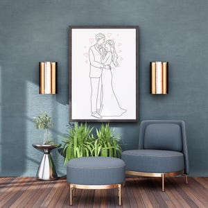 Peut inclure: Un dessin au trait encadré d'un couple enlacé, entouré de cœurs roses, est accroché à un mur bleu-vert. La pièce comprend une chaise grise, un pouf et une table d'appoint avec des plantes et des appliques murales dorées, créant un cadre moderne et romantique.