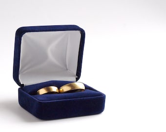 May include: Two gold wedding bands in a blue velvet ring box.