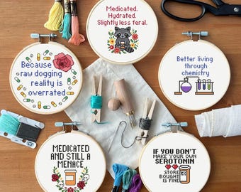 May include: Five embroidery hoops with different funny sayings. The sayings are "Because raw dogging reality is overrated", "Medicated and still a menace", "Medicated. Hydrated. Slightly less feral.", "Better living through chemistry", and "If you don't make your own serotonin store bought is fine".