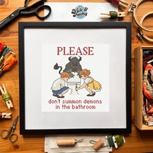 Puede incluir: Imagen de un bordado enmarcado en un marco negro. La obra presenta la palabra "PLEASE" sobre una escena de dibujos animados con dos niños y un demonio cerca de un inodoro. El texto de abajo dice "don't summon demons in the bathroom."