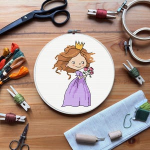 May include: A cross-stitch embroidery hoop featuring a cartoon princess in a purple dress, holding roses, and wearing a gold crown. The embroidery is surrounded by craft supplies, including scissors, thread, and wooden hoops, on a wooden surface.