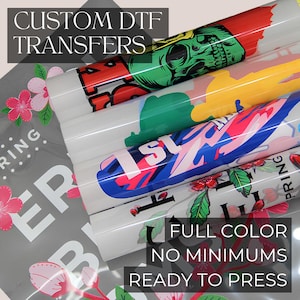 Puede incluir: Cuatro rollos de transferencias DTF personalizadas con varios diseños gráficos, incluyendo una calavera verde, formas abstractas y patrones florales. El texto CUSTOM DTF TRANSFERS y FULL COLOR NO MINIMUMS READY TO PRESS es visible.