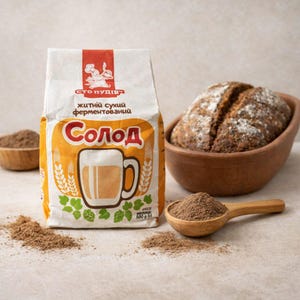 Puede incluir: Una bolsa de papel blanca y naranja de malta de centeno fermentada seca Sto Pudiv marcada con 500 g, con un gráfico de una jarra y trigo. Al lado hay un cuenco de madera con un pan oscuro y una cuchara de madera llena de polvo de malta marrón.