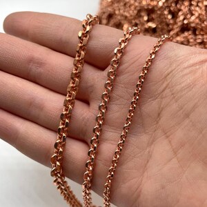 May include: Close-up of three different styles of copper-colored chain. The chains vary in thickness and link design, with a bright, metallic finish. The chains are displayed against a neutral background, highlighting their texture and color. The chains are likely for jewelry making.