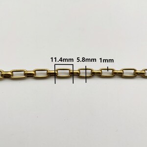 May include: Close-up of a gold-colored chain with rectangular links. The image shows measurements of 11.4mm, 5.8mm, and 1mm. The chain is displayed against a white background.