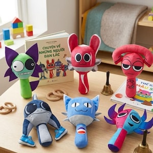 Op de afbeelding: Een collectie van zes kleurrijke pluche speelgoedfiguren met unieke ontwerpen, waaronder een groen katachtig figuur, een rood wezen, een roze personage met een gebogen hoofd, een grijze haai-achtige knuffel, een blauwe kat en een tweekleurig speeltje.