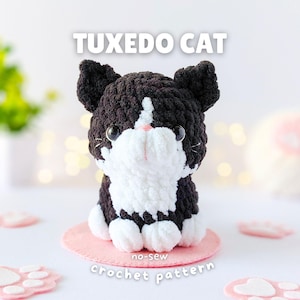 May include: A plush crochet tuxedo cat toy with black and white yarn, featuring large dark eyes, a small pink nose, and white paws. The text TUXEDO CAT is displayed above the cat, and the text no-sew crochet pattern is displayed below the cat.