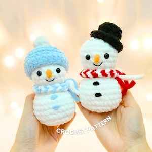 Puede incluir: Dos muñecos de nieve de ganchillo, uno con gorro y bufanda azules, el otro con gorro negro y bufanda roja. Ambos tienen ojos negros, narices naranjas y detalles de botones negros. El texto "CROCHET PATTERN" es visible.