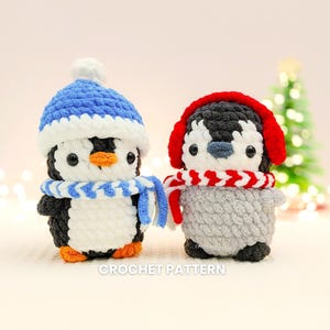 Op de afbeelding: Twee handgemaakte gehaakte pinguïns. Eén draagt een blauw-witte muts en sjaal, de ander een rode oorwarmer en sjaal. De pinguïns zijn zwart, wit en grijs met oranje snavels en voeten. De tekst "CROCHET PATTERN" staat onderaan.