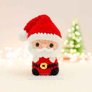 Könnte beinhalten: Eine gehäkelte Weihnachtsmannfigur mit rotem Hut und Anzug, weißem Bart und Besatz sowie schwarzen Stiefeln. Die Figur hat eine goldene Gürtelschnalle und schwarze Augen. Der Text "CROCHET PATTERN" ist unten sichtbar.