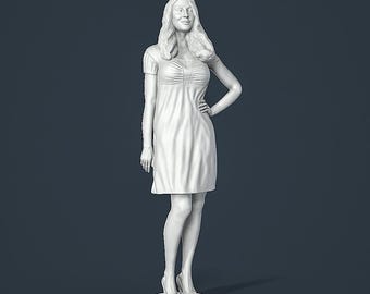 Può includere: Scultura bianca stampata in 3D di una donna con un vestito a maniche corte e tacchi. La figura è in piedi su una base circolare con una mano sul fianco. La donna ha lunghi capelli ondulati e sorride.