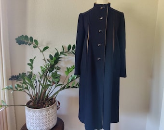 Peut inclure: Un long manteau noir avec des garnitures et des boutons dorés. Le manteau a un col montant et une fermeture à simple boutonnage.