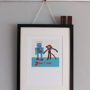 May include: Framed art print with a blue robot and a monkey holding hands, with the words "You + me" in red. The print is in a black frame and hangs from a wall hook.
